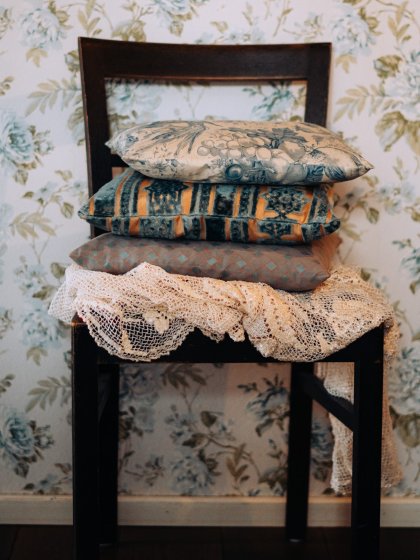 Detail van een boutique hotel interieur met vintage stoel, sierkussens en bloemenbehang, door cestsjoukje