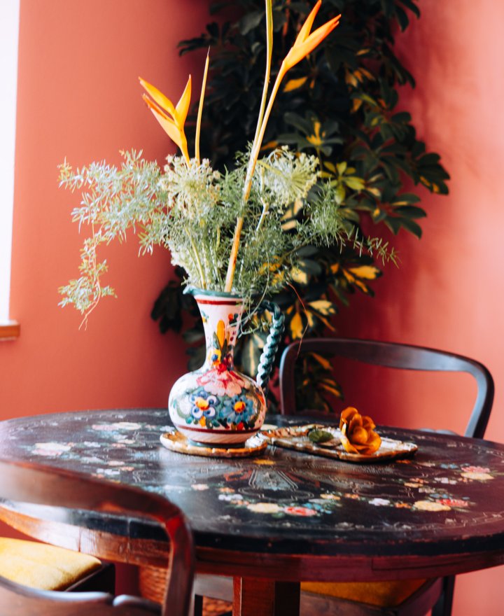 Ronde tafel met een bloemvaas tegen een warme rode wand, boutique hotel interieur door cestsjoukje