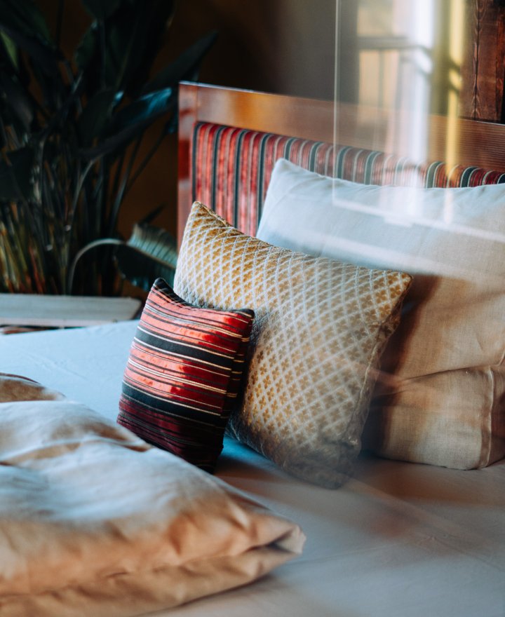 Hotelkamer met gestreepte fluwelen kussens en een glazen pendellamp, door cestsjoukje