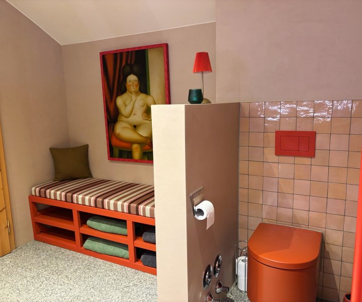 Badkamer in een vakantieappartement met een oranje wc uit de Vitrium-lijn van Duravit en een gestreepte bank in Liberty-stof, door cestsjoukje