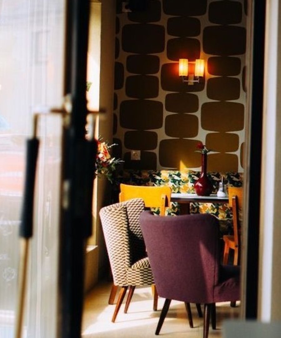 Cafe-interieur met doorkijk, retrobehang en fauteuils, door cestsjoukje