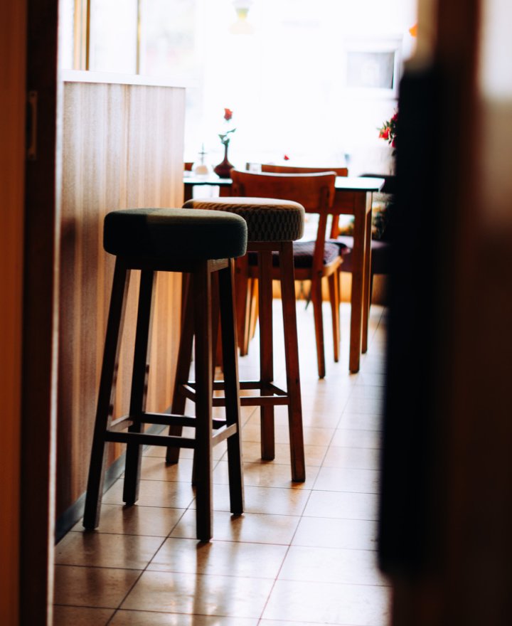Cafe-interieur met barkrukken op een gele terrazzovloer, door cestsjoukje